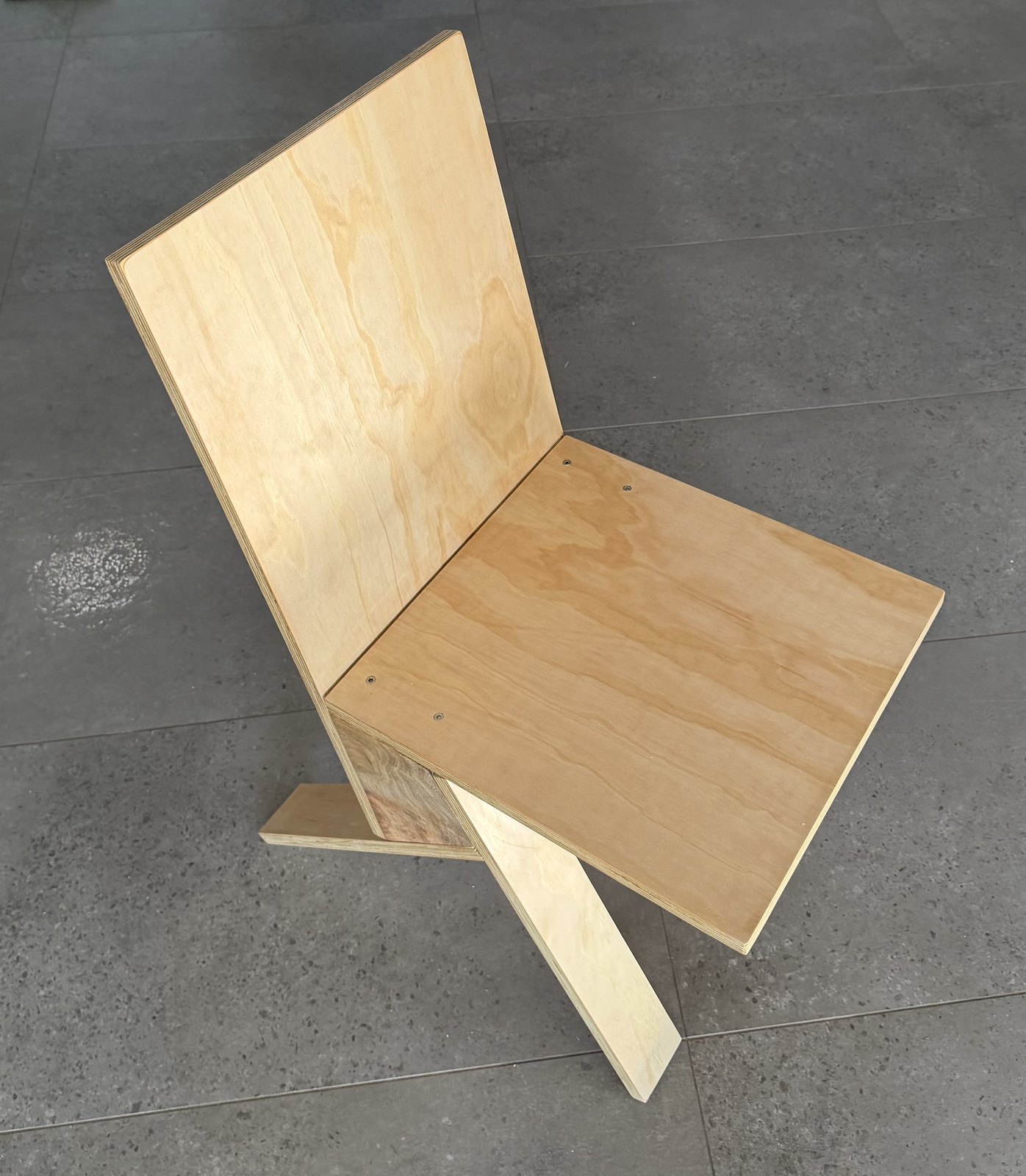 The wood-bracket stave chair: five plywood members a side on narrow crossed legs, on grey tile