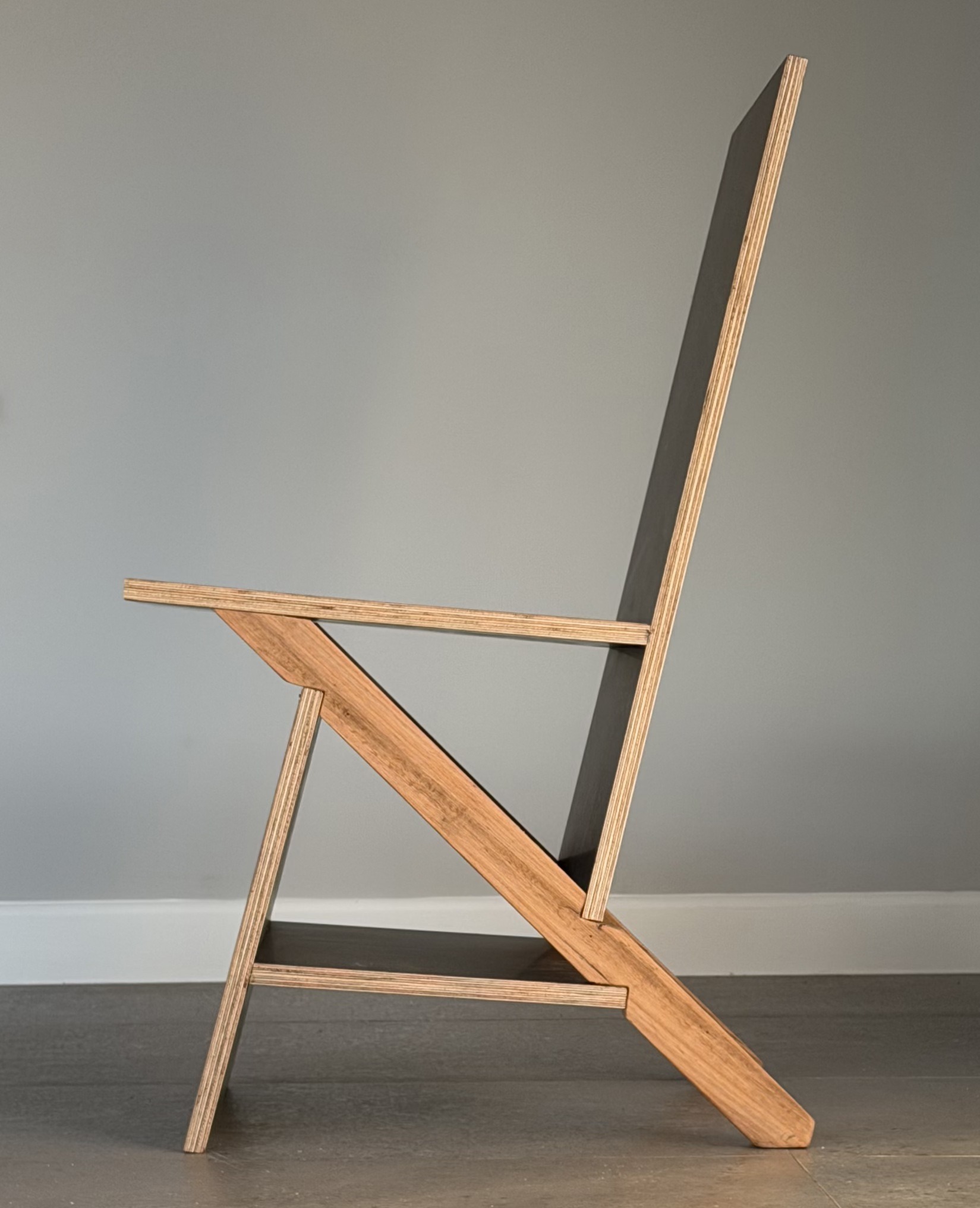 The K2 keel chair square to its side against a plain wall: two triangles sharing a long raking spine