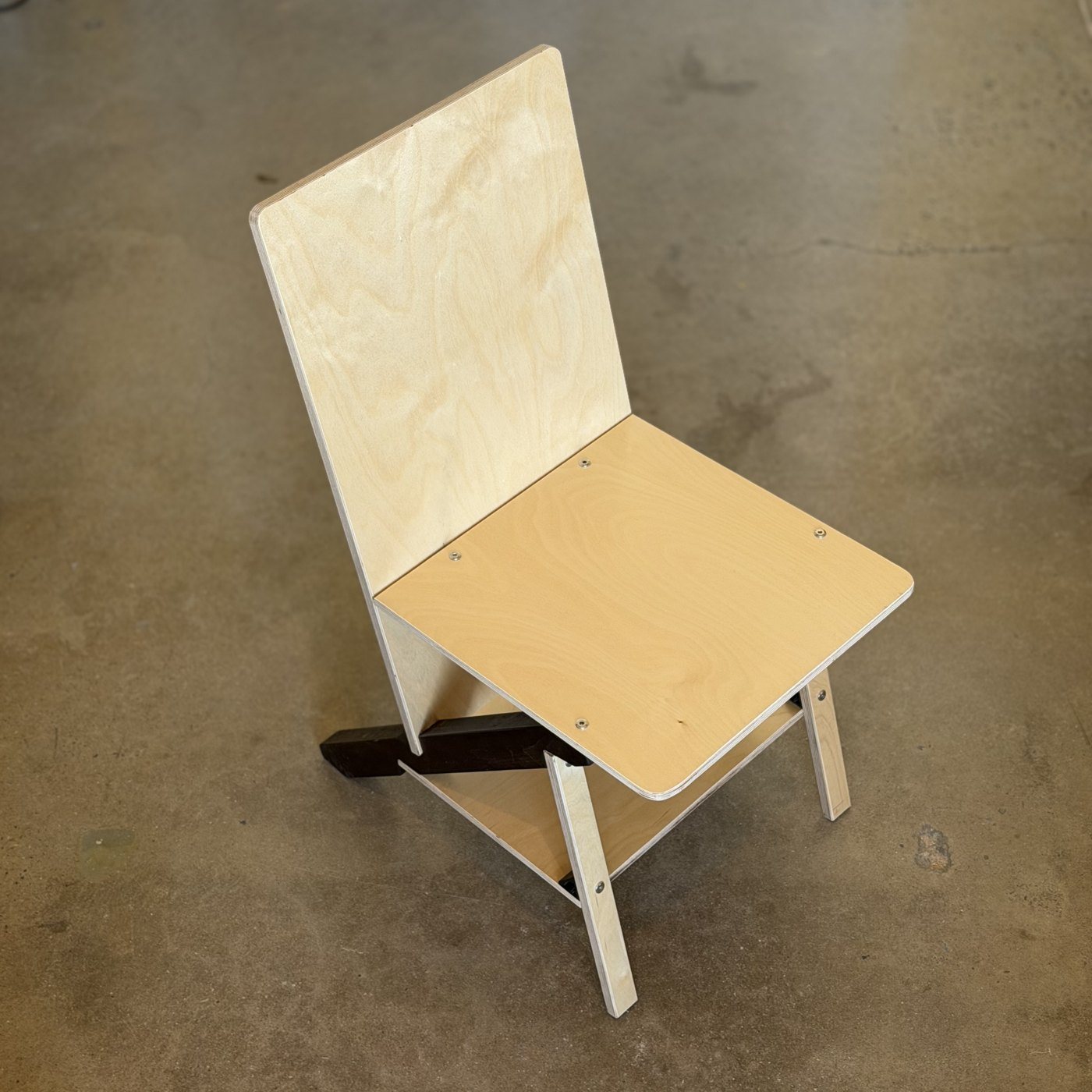 A Keel Panel chair in birch plywood with a dark cherry keel, three-quarter view