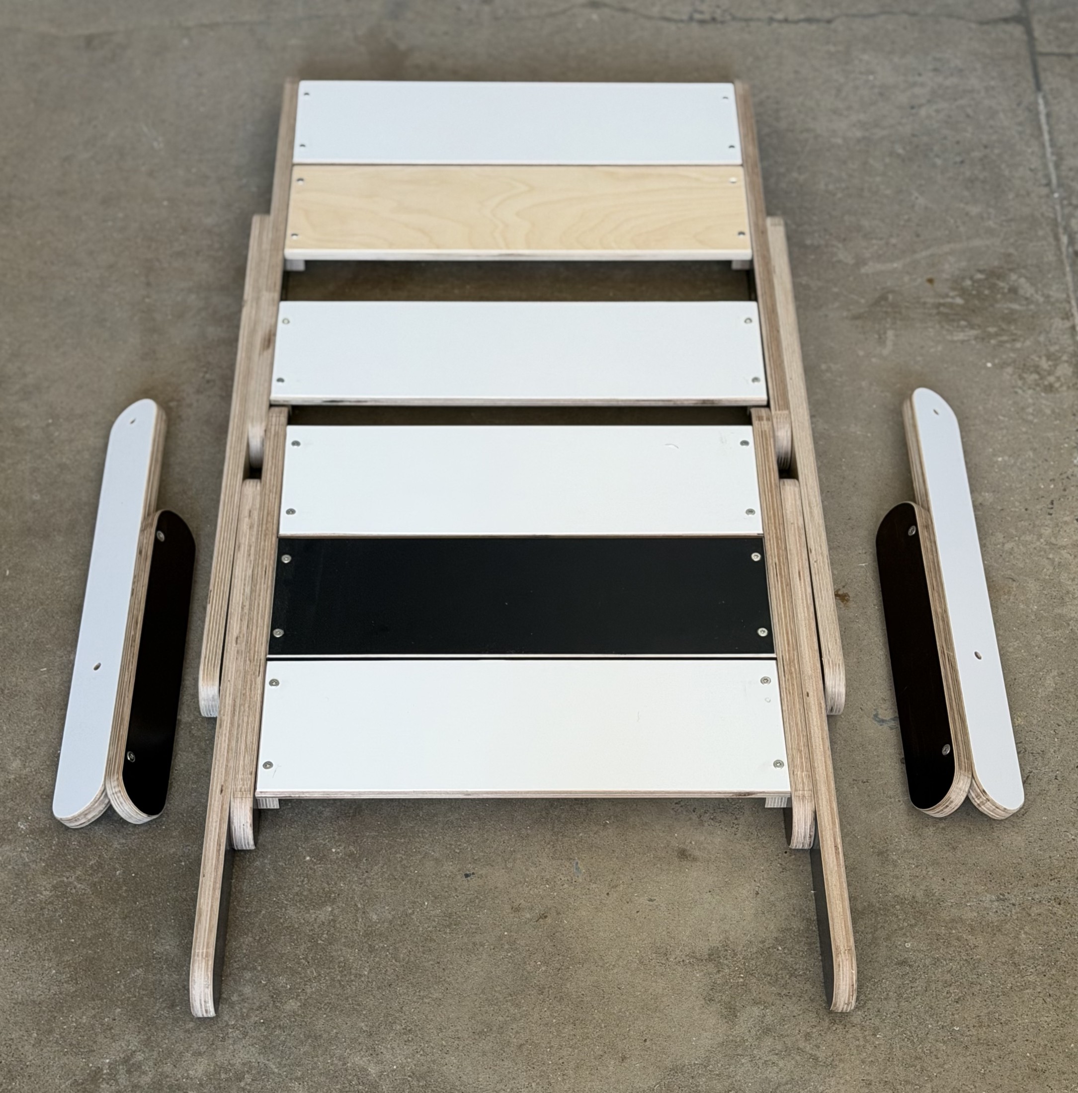 The Keel Truss chair folded flat on the floor with its two arms beside it